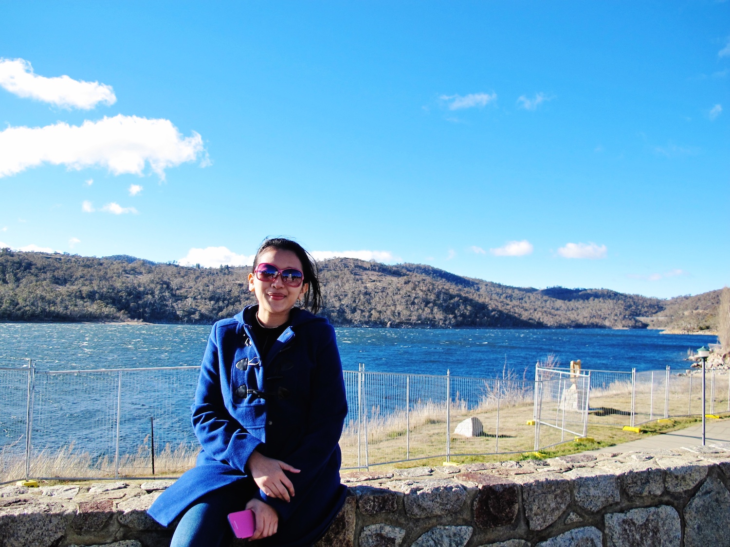 A woman with sunglasses wearing blue coat sitting